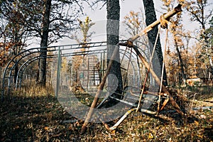 Creepy abandoned children playground among autumn trees, rusty swing