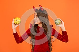 Creepy crawly. Happy little girl hold pumpkins orange background. Small child dressed up as creepy devil. Creepy look photo
