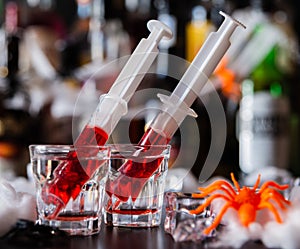 creepy halloween party cocktails with syringes of grenadine syrup as blood, shot drinks at party