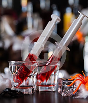 creepy halloween party cocktails with syringes of grenadine syrup as blood, shot drinks at party