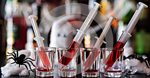 creepy halloween party cocktails with syringes of grenadine syrup as blood, shot drinks at party