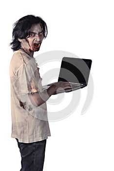 Creepy male zombie typing with laptop