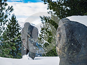 Creepy scary gothic snow covered statue of a spirit ghost on a mountain in a forest during winter