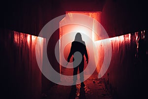 Creepy silhouette with knife in the dark red illuminated abandoned building. Horror about maniac concept photo