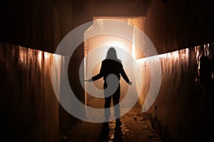 Creepy silhouette of unknown man with knife in dark abandoned building. Horror about maniac concept