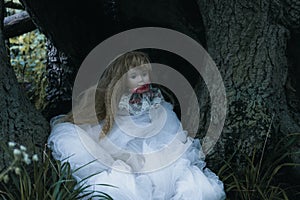 A creepy spooky doll, sitting in a forest. With a dark, muted edit