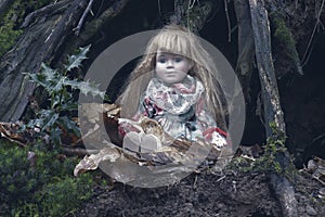 A creepy spooky doll, sitting under a tree in a forest. With a dark, muted edit