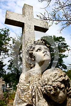 Creepy stone cross with statue in the cemetery