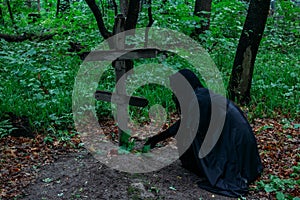 Creepy witch in black in spooky abandoned cemetery