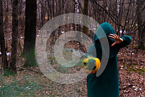 A creepy witch holds a steaming pumpkin in a deep forest. Jack o lantern with green smoke for halloween