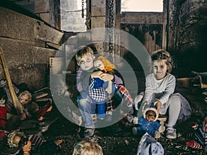 Creepy young children sitting with old dolls in a barn