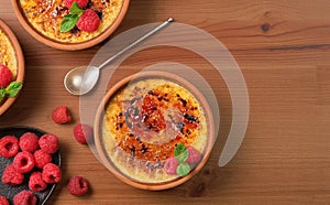 Creme brulee dessert with raspberries and mint leaves on a wooden table, top view with copy space. Delicious dessert with cream
