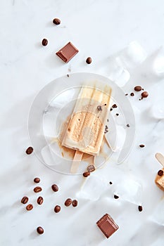 Creme brulee ice cream lolly pop with coffee beans and piece chocolate on a marble ice background, top view