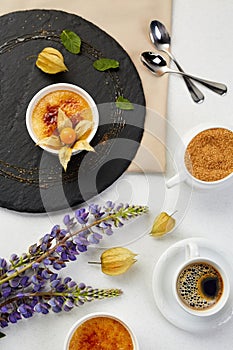 Creme brulee with Physalis and brown sugar. Creme brulee dessert with lavender and coffee on black shale.