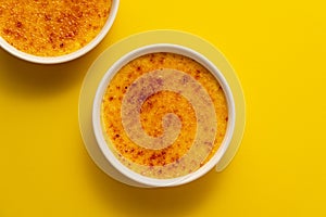 Creme brulee in ramekin isolated on bright yellow color background. photo
