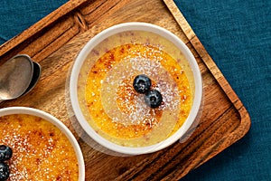Creme brulee in ramekin on wooden tray on dark linen tablecloth. Spanish crema catalana, top view photo