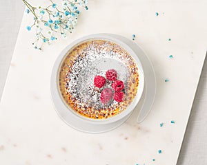 Creme brulee. Traditional French vanilla cream dessert with powdered sugar and raspberry photo