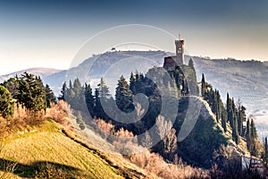 Crenellated clock tower among hills in the fog photo