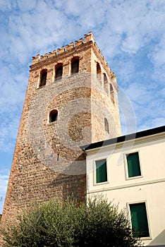 Crenellated tower olive tree and sky with white clouds in Monselice in the Veneto (Italy)