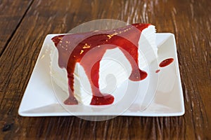 Crepe cake with strawberry sauce on wooden table