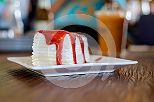 Crepe cake with strawberry sauce on wooden table