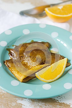 Crepe suzette in caramel sauce on a plate with a slice of orange. French dessert.