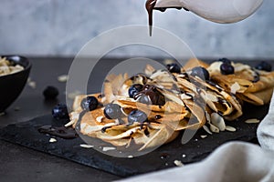 Crepes with blueberries almond flakes and chocolate sauce on black.