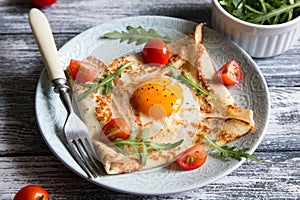 Crepes with eggs, cheese, arugula leaves and tomatoes. Galette complete. Traditional dish galette sarrasin