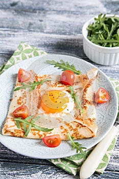 Crepes with eggs, cheese, arugula leaves and tomatoes. Galette complete. Traditional dish galette sarrasin