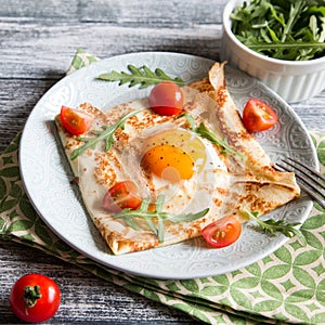 Crepes with eggs, cheese, arugula leaves and tomatoes. Galette complete. Traditional dish galette sarrasin