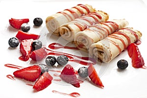 Crepes with fresh berries. Pancakes stack with Strawberry, blueberry and syrup, isolated on a white background