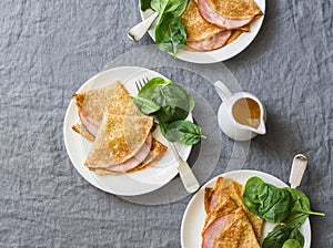Crepes with ham and spinach. Delicious, nourish breakfast on a grey background