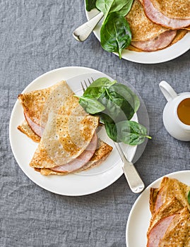 Crepes with ham and spinach. Delicious, nourish breakfast or snack on a grey background