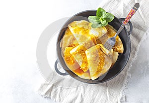 Crepes with Orange Sauce in a cast iron pan. Traditional French crepe Suzette with orange sauce.