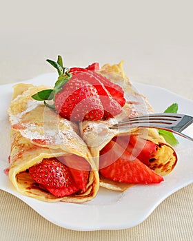 Crepes with strawberries sprinkled with powered sugar