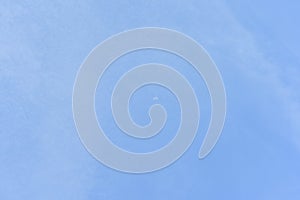 The crescent moon appears on daytime blue sky with white clouds