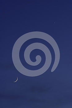 Crescent moon on the night sky seen trough clouds