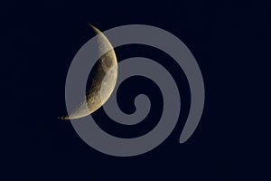 Crescent moon on the night sky seen trough clouds