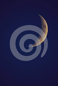 Crescent moon on the night sky seen trough clouds