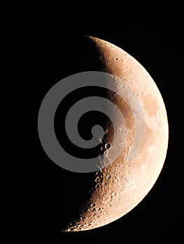 Crescent Moon in sky showing crater detail in orange color