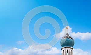 Crescent moon and star at a top of Old Mosque over the clouds on blue sky background. The Mosque is an important for Islamic