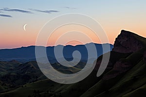 crescent moon between two hill peaks