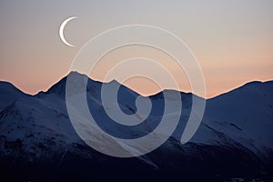 crescent moon between two hill peaks