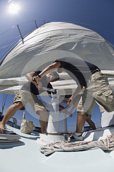 Crew Members Operating Windlass On Yacht