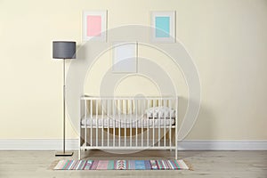 Crib and floor lamp near light wall in baby room