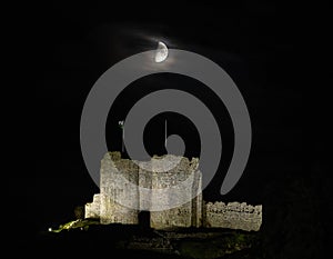 Criccieth castle floodlit at night under a half moon in Criccieth, Gwnydd, Wales