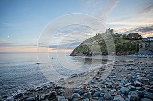 Criccieth Castle at sunset with moon in the sky seen from Criccieth beack, Gwnydd, Wales
