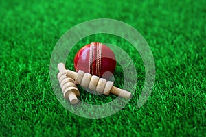 Cricket ball and bails on green grass pitch