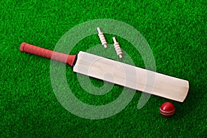 Cricket bat and ball place on cricket ground pitch, green grass