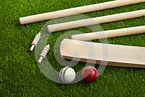 Cricket bat ball stumps and bails placed on green grass cricket pitch background